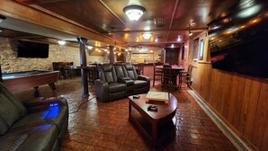 Un rincón acogedor con bar, mesa de billar, sillones de cuero y mesa de futbolín.