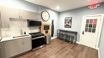 Een moderne keuken met een inbouwoven, een spoelbak en een grote klok aan de muur.