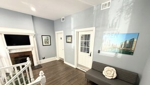 Ein Wohnzimmer mit Kamin, einer Couch, einer Treppe und einer Tür.