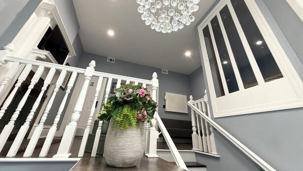 Eine Treppe mit weißen Geländern und einem Chandelier.