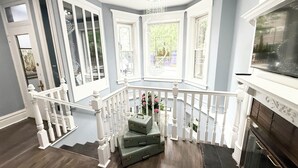 Ein Eckzimmer mit Treppe, Kamin und großen Fenstern.