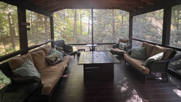 Un espace extérieur abrité, doté d’un plafond en bois, de canapés confortables et d’une table centrale.