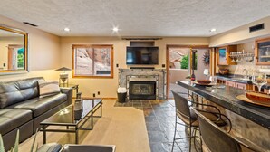Ein Wohnzimmer mit Kamin, Fernseher, Bar und Esstisch.