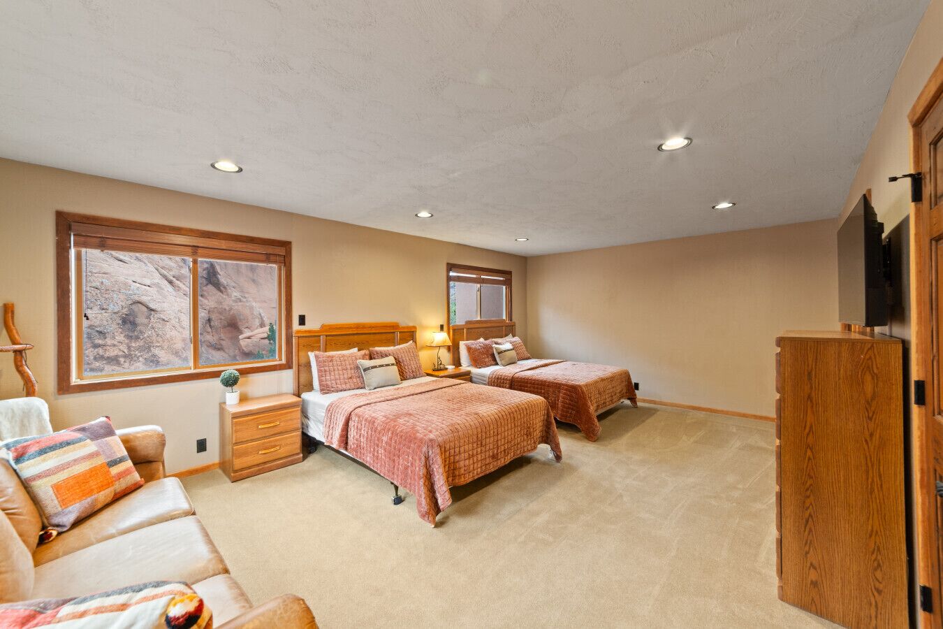 Ein Schlafzimmer mit zwei Betten, einem Holzschrank, einem Nachttisch, einem Stuhl und einem großen Fenster mit Blick auf Felsen.