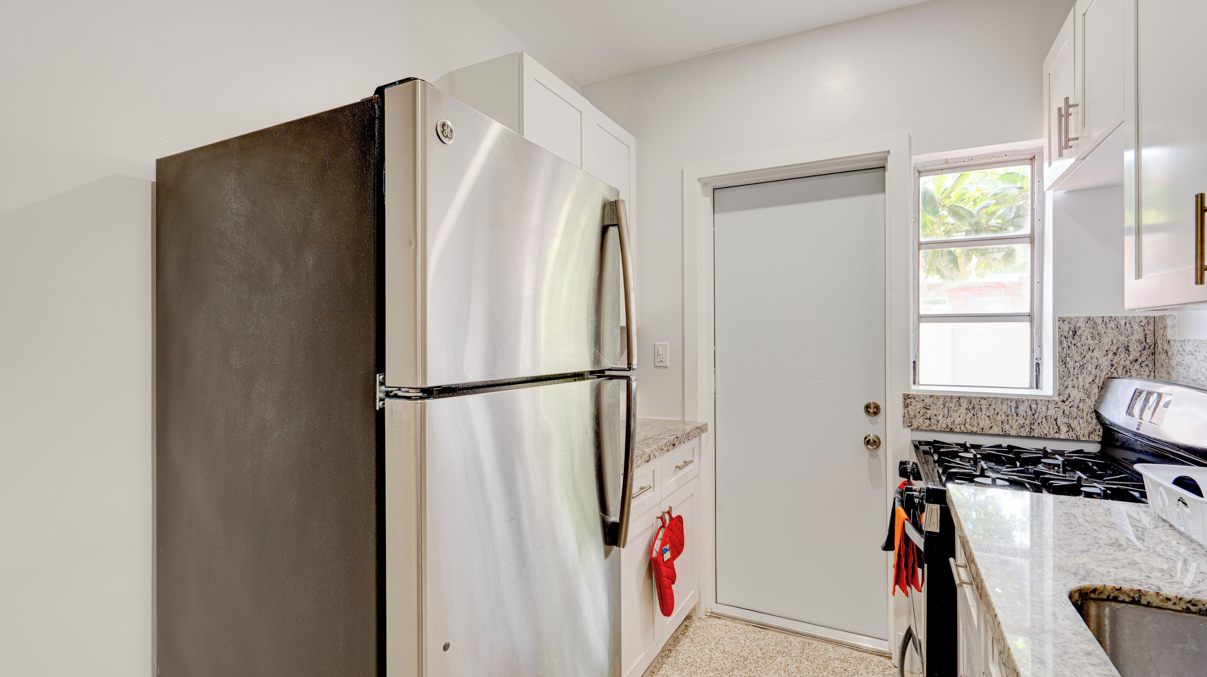 Una cocina con un refrigerador de acero inoxidable, estufa y armarios blancos.