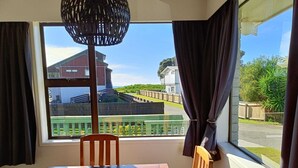 Um quarto com uma janela grande, uma mesa de madeira e uma cadeira.