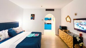 Une chambre d’hôtel avec un lit, une télévision, un bureau et une salle de bain visible à travers une arche.