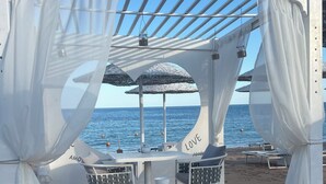 A beachside outdoor seating area with white canopies and umbrellas, a table with chairs, and a view of the sea. - Domina Coral Bay 1 or 2 rooms sea view terrace  (South Sinai Governorate)