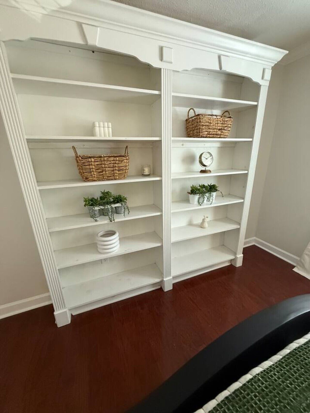Un mueble blanco de varios niveles con estantes, cestas y plantas en macetas.