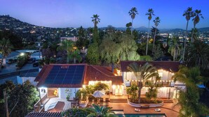 A residential property with a swimming pool, solar panels, and a view of a cityscape at dusk. - Luxury 5BR Villa - Pool, Spa, Movie Theater, Game Room, Bar, & Outdoor Dining (La Mesa)