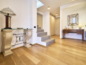 A modern interior with a staircase, a console table with a lamp, and a mirror on the wall.