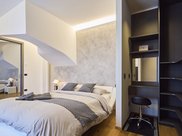 A modern bedroom with a large bed, a desk, and a chair.