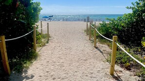 A sandy pathway leading to a beach with a clear view of the ocean and city skyline. - Fully Remodeled 2 Bedroom with Direct Beach Access (Miami Beach)