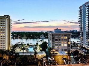 A high-rise hotel with a view of a body of water and a pool area.