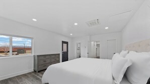 A bedroom with a large bed, a dresser, and a window. - Modern 3-bed, 2-bath suite with a beautiful view of Topaz Lake. (Gardnerville)