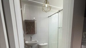 Un baño moderno con lavamanos, inodoro y cabina de ducha de cristal.
