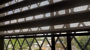 Ventana con vista a un área residencial, que presenta una estructura de celosía y una terraza de madera.
