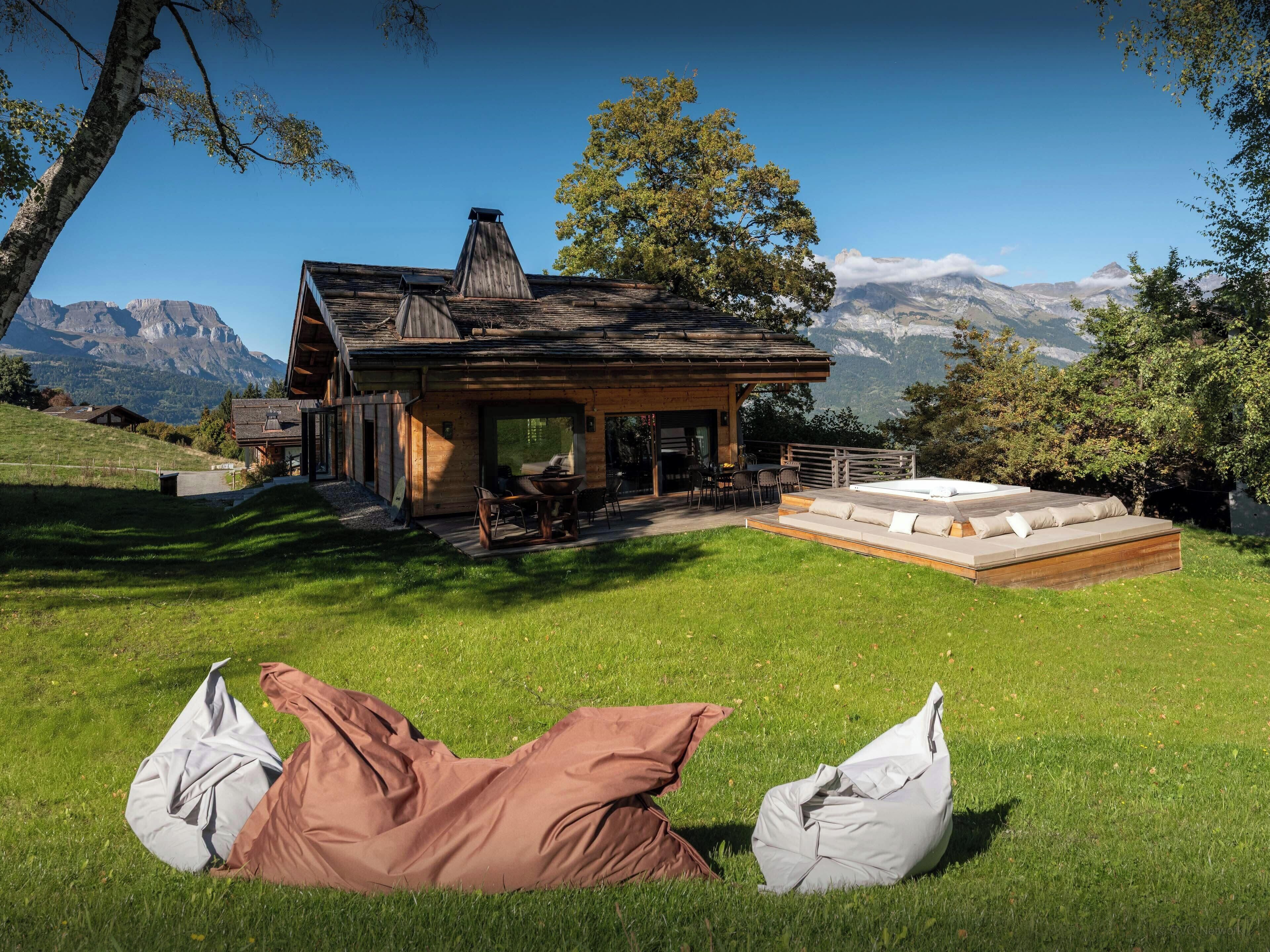 Une cabane en bois dotée d’une terrasse, d’un jacuzzi et offrant une vue sur les montagnes.