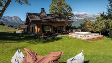 Une cabane en bois dotée d’une terrasse, d’un jacuzzi et offrant une vue sur les montagnes.