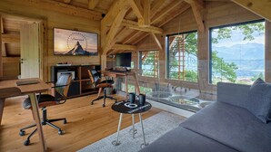 A wooden cabin interior with a desk, computer, and seating area. - Chalet RevAlp - All-season holidays with private sauna - OVO Network (Combloux)