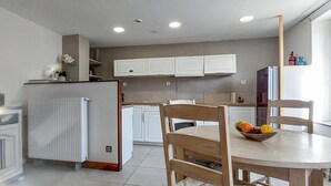 A modern kitchen with white cabinets, a central island, and a dining area with wooden chairs and a table.