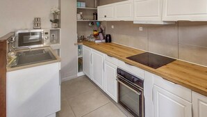 A compact kitchen with white cabinetry, a wooden countertop, a built-in oven, and a microwave.