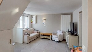 A compact living space with a sofa, a small table, a TV, and a cabinet.