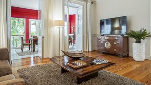 A living room with a wooden coffee table, a TV, and a cabinet. - XIX Writer’s Belle Époque Villa • Central Funchal • Tropical Garden • BBQ (Funchal)
