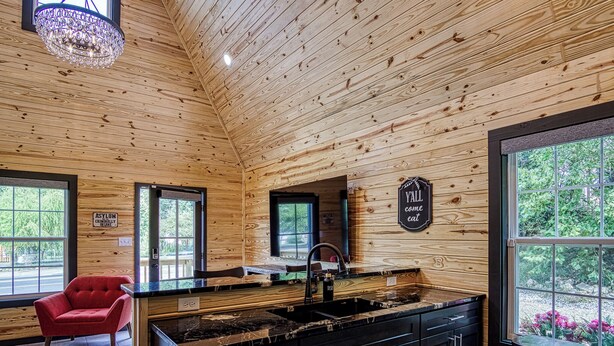 A wooden interior with a kitchen, a red armchair, and a sign that says "YALL Come Eat".
