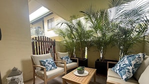 A cozy outdoor seating area with wooden furniture, a small table, and potted plants.