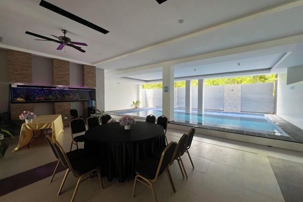 A modern indoor space with a pool, a dining area with chairs and a table, and a television. - Dreamweavers Hotel by RedDoorz (Koronadal City)