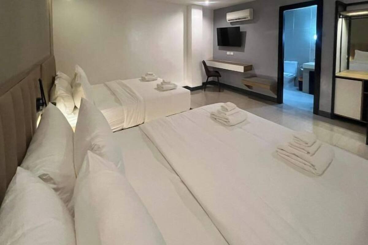 Une chambre d’hôtel avec deux lits, un bureau, une chaise et un téléviseur.