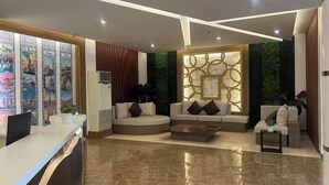 A modern reception area with a reception desk, two sofas, a coffee table, and decorative wall panels. - Dreamweavers Hotel by RedDoorz (Koronadal City)