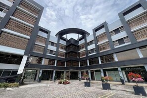 A modern building with a central atrium, multiple floors, and a Manufuge store. - Dreamweavers Hotel by RedDoorz (Koronadal City)