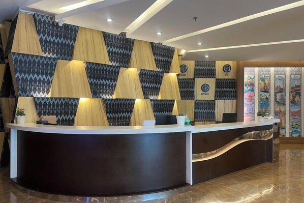 A reception desk with a patterned wall behind it, a curved counter, and a tiled floor. - Dreamweavers Hotel by RedDoorz (Koronadal City)