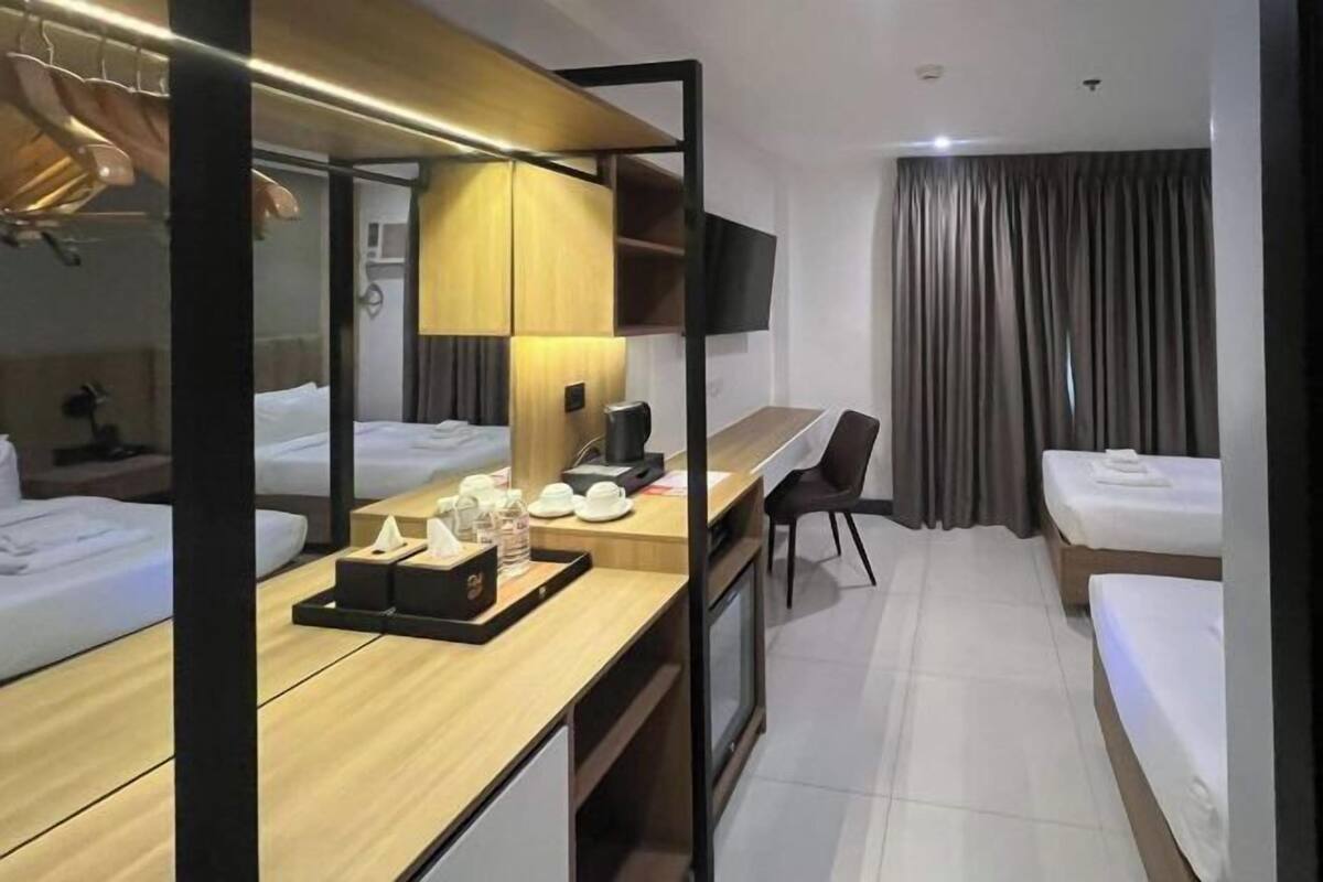 Une chambre d’hôtel avec deux lits, un bureau avec une chaise, une télévision et une armoire.