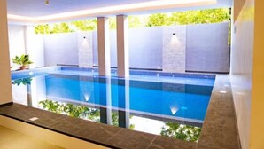 A modern indoor swimming pool with clear glass walls, surrounded by a minimalist design and natural light. - Dreamweavers Hotel by RedDoorz (Koronadal City)