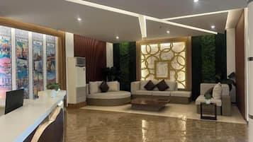 Un moderno vestíbulo de hotel con recepción, zona de estar y paneles decorativos en la pared.