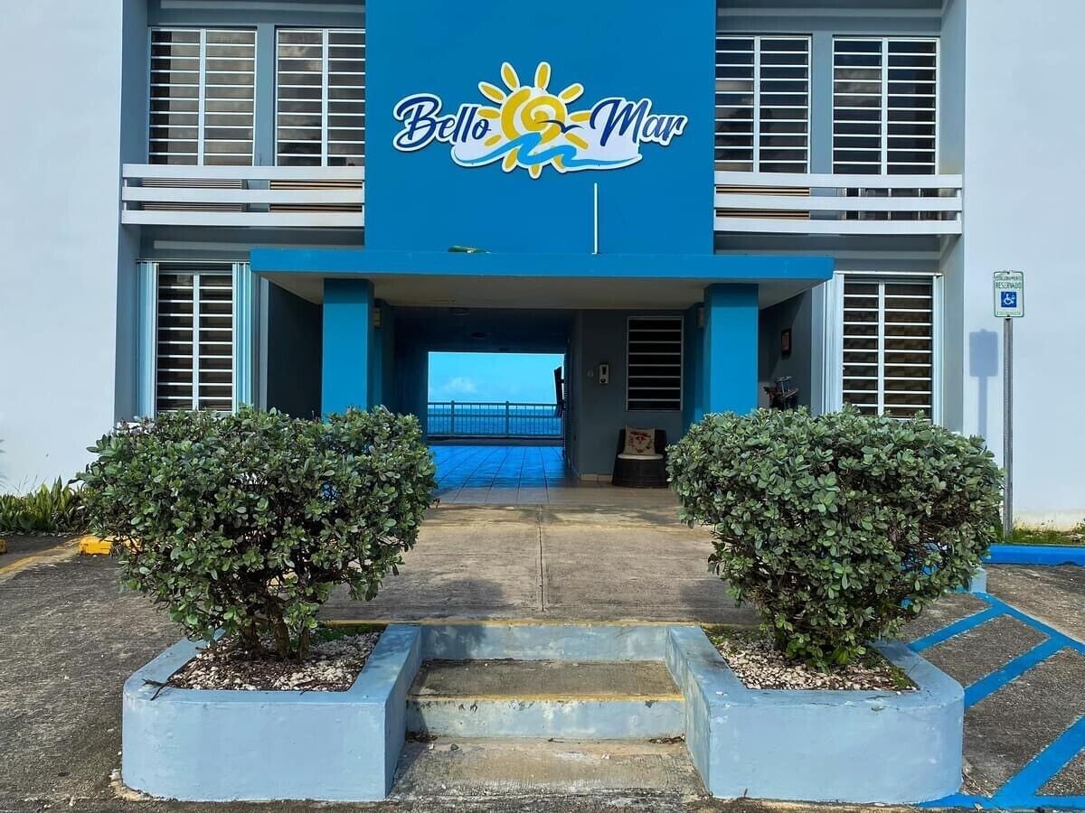 A hotel entrance with a blue facade, a sign reading 'Bello Mar', and a wheelchair-accessible entrance.
