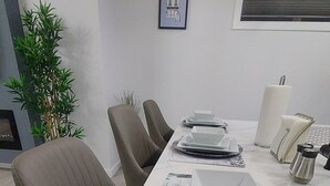 A modern dining area with a white table, brown chairs, and a potted plant.