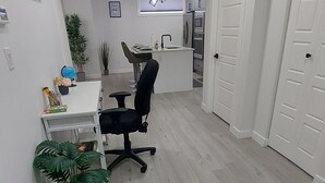 A modern kitchen with white cabinets, a black chair, and a dining table. There are potted plants and a globe on the table.