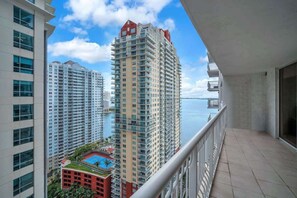 A high-rise building with multiple balconies, a pool, and a view of the sea.