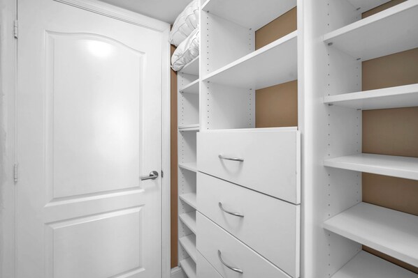 Ein weißer Kleiderschrank mit mehreren Schubladen und Regalen, einer weißen Tür und einer braunen Seitenwand.