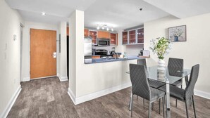 Une cuisine moderne dotée d’un îlot central, d’un coin repas avec une table et des chaises en verre, et d’une porte en bois.