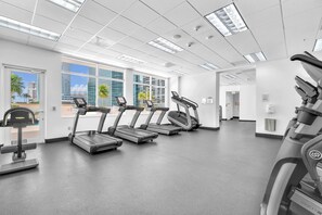 Un gimnasio con cintas de correr, una bicicleta estática y una máquina de remo.