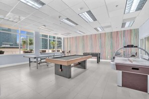 A modern indoor recreational area with a pool table, foosball table, and exercise equipment.