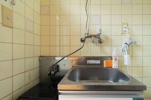 A small kitchen with a stainless steel sink, a black countertop, and a tiled backsplash.
