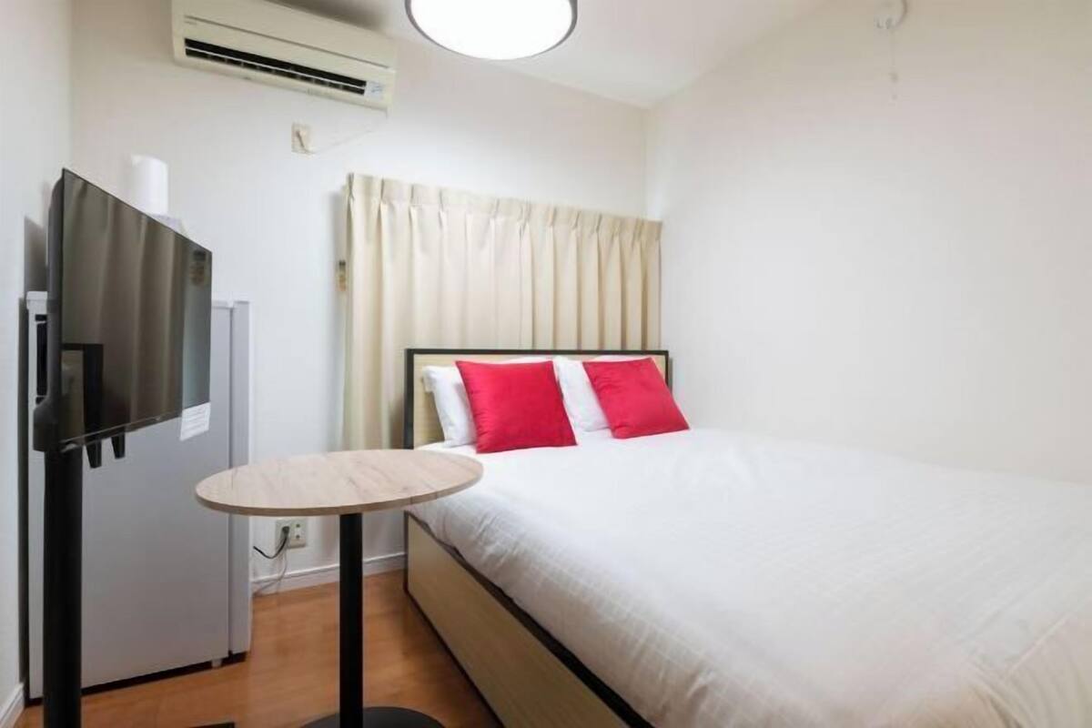 Une chambre d’hôtel équipée d’un lit, d’une petite table ronde, d’un téléviseur et d’un appareil de climatisation.