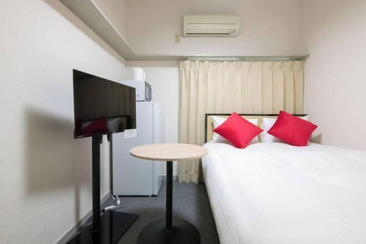 Une chambre d’hôtel équipée d’un lit, d’une télévision, d’une petite table et d’un appareil de climatisation.