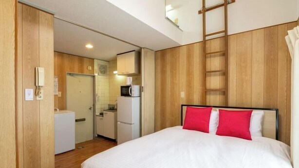 Una habitación de hotel con cama, armario, kitchenette y baño.